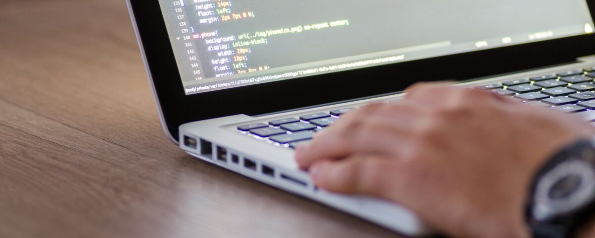 Person coding on a laptop with HTML code on screen, showcasing development work.