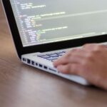 Person coding on a laptop with HTML code on screen, showcasing development work.