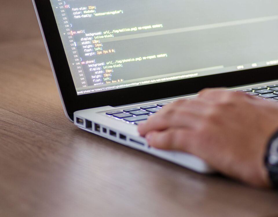 Person coding on a laptop with HTML code on screen, showcasing development work.