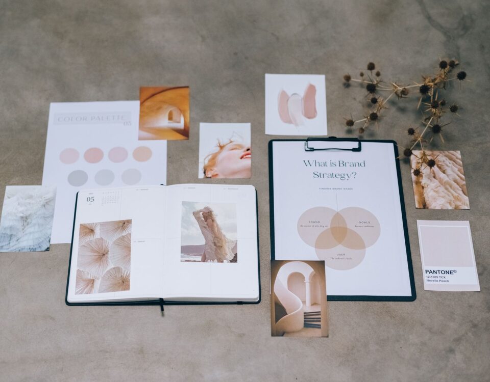 A flat lay of branding elements with color palettes and strategic planning documents on a concrete surface.