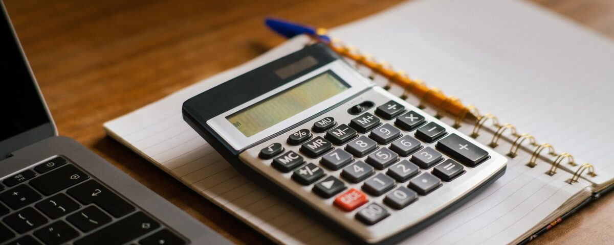 Calculator and open laptop on wooden desk, ideal for financial or accounting tasks.