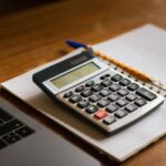 Calculator and open laptop on wooden desk, ideal for financial or accounting tasks.