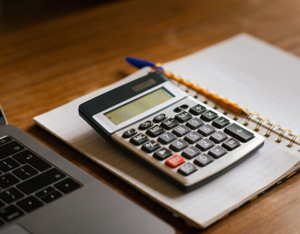 Calculator and open laptop on wooden desk, ideal for financial or accounting tasks.