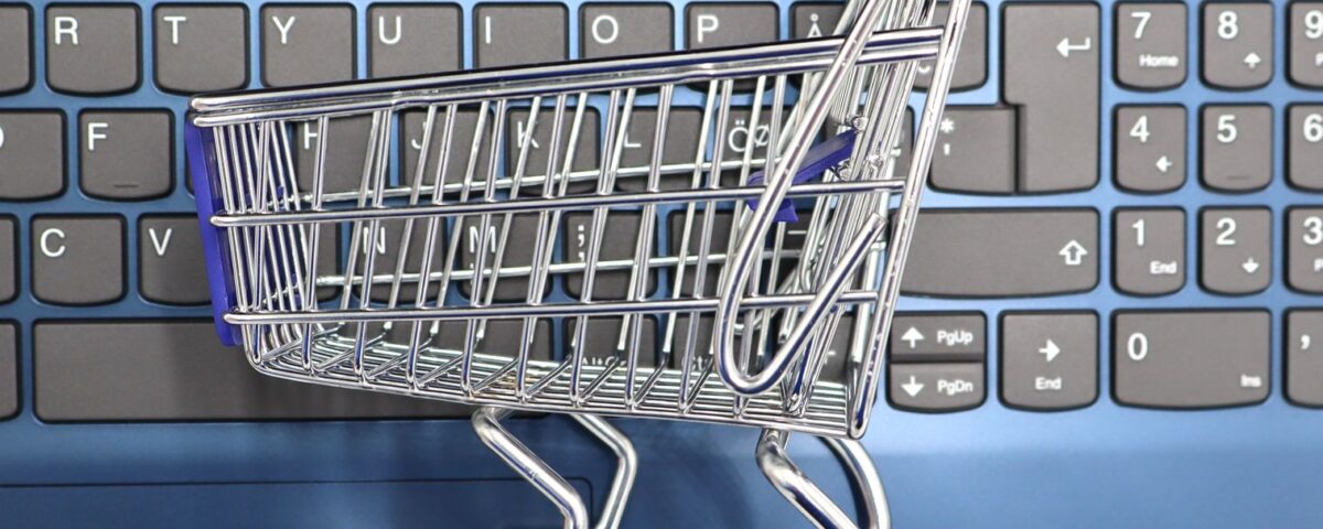 A miniature shopping cart placed on a laptop keyboard symbolizing online shopping and e-commerce.