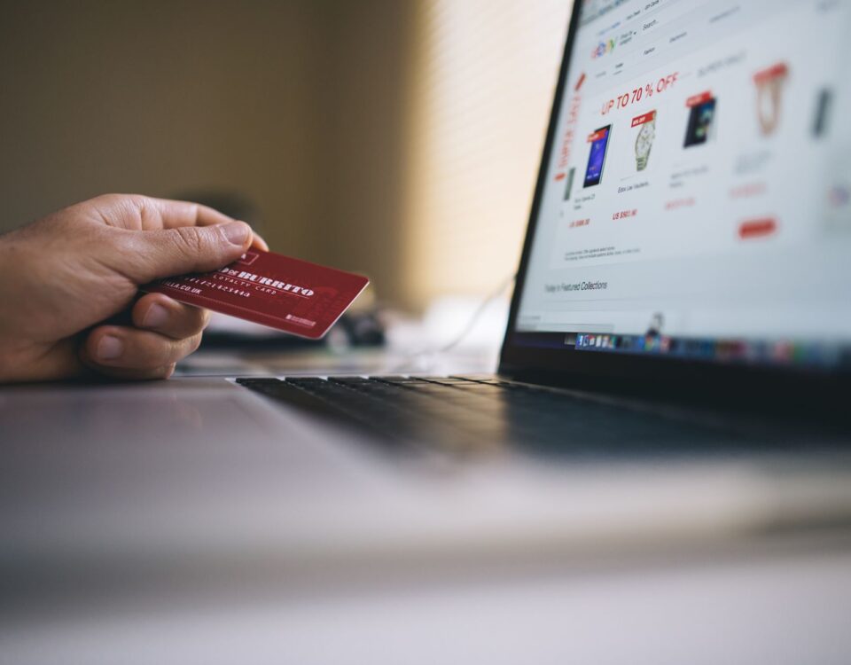 Person holding a credit card while shopping online on a laptop, indicating ecommerce transactions.