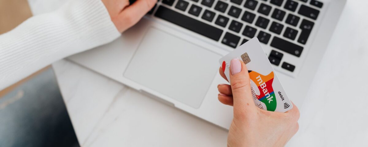 Close-up of a person using a laptop and holding a credit card for online shopping.