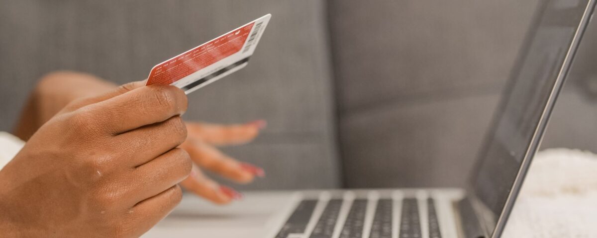Close-up of a person using a credit card for online shopping on a laptop.