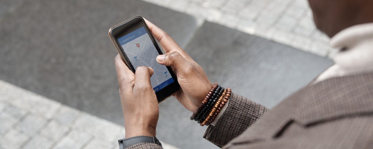 A stylish professional adult using a smartphone with a navigation app on an urban street.