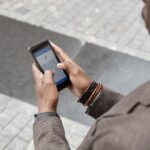 A stylish professional adult using a smartphone with a navigation app on an urban street.