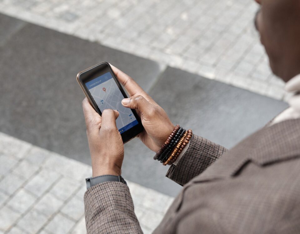 A stylish professional adult using a smartphone with a navigation app on an urban street.