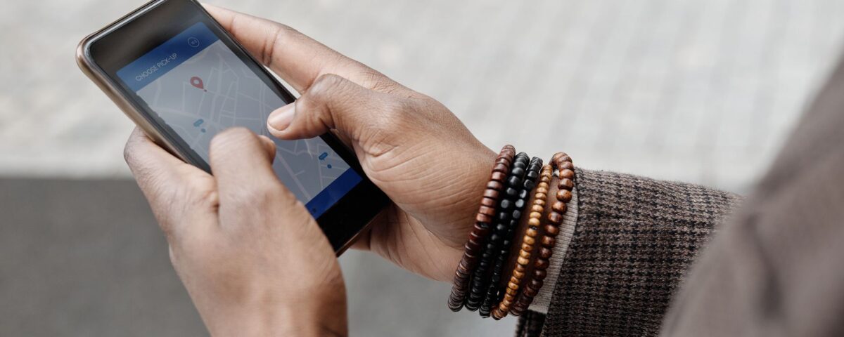 Close-up of hands with bracelets navigating on smartphone using GPS app outdoors.