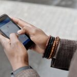 Close-up of hands with bracelets navigating on smartphone using GPS app outdoors.