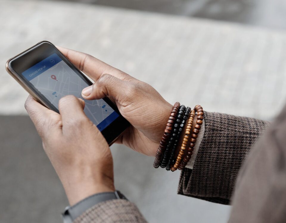 Close-up of hands with bracelets navigating on smartphone using GPS app outdoors.