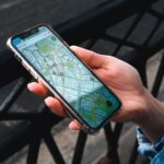 An outdoor close-up of a hand holding a smartphone displaying a map application.