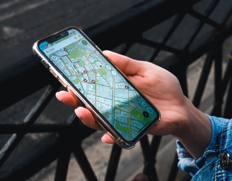 An outdoor close-up of a hand holding a smartphone displaying a map application.